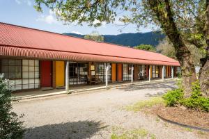 a building with a red roof and a tree at The Harrietville Snowline Hotel in Harrietville