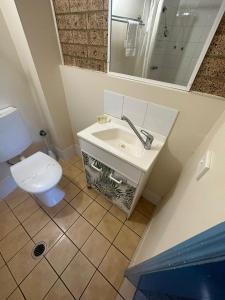 Coolum Budget Accommodation في كولوم بيتش: حمام مع حوض أبيض ومرحاض