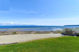 a view of a beach with the ocean in the background at Oceanfront Loft - amazing views! in Qualicum Beach