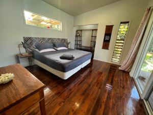 a bedroom with a bed and a wooden floor at Avocado Retreat in Rarotonga