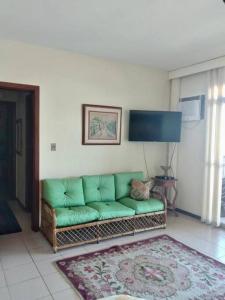 ein Wohnzimmer mit einer grünen Couch und einem Teppich in der Unterkunft Edifício Luar da Praia in Cabo Frio