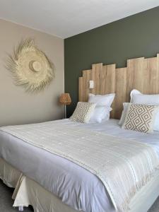 um quarto com uma cama grande com lençóis brancos e almofadas em Hôtel BO & MIA em La Baule