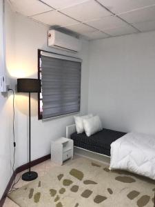 um pequeno quarto com uma cama e uma janela em Cherating Bayu Guesthouse em Cherating
