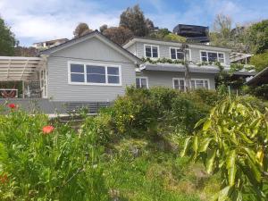 a white house with a garden in front of it at Tahuna Hills Guesthouse in Nelson