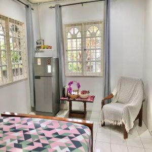uma sala de estar com uma cadeira e um frigorífico em Basari Guest House em Lundu