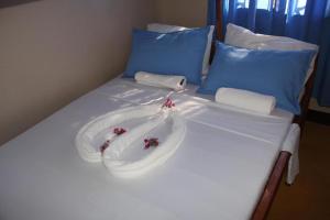 Una cama con sábanas blancas y flores. en Mafia Neptune Villa Lodge, en Utende