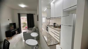 a kitchen with white cabinets and a white refrigerator at Apto próximo ao roteiro do vinho in São Roque
