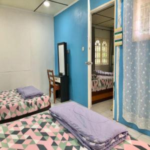 a bedroom with two beds and a blue wall at Basari Guest House in Lundu