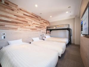 una fila de tres camas en una habitación en Super Hotel Hakodate, en Hakodate