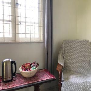 LunduにあるBasari Guest Houseの椅子と窓の横のテーブルの上に置かれた鉢