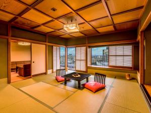 a living room with a table and chairs and windows at Yukai Resort Premium NEW MARUYA Hotel in Kaga