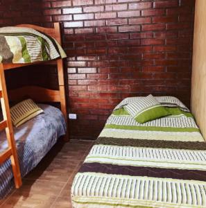 Cabañas Altura de Varillar في Varillar: سريرين بطابقين في غرفة مع جدار من الطوب
