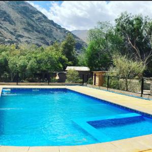 uma grande piscina azul com montanhas ao fundo em Cabañas Altura de Varillar em Varillar
