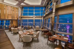 un restaurante con mesas, sillas y ventanas grandes en Grand Hyatt Shanghai en Shanghái