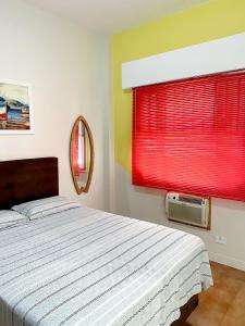 a bedroom with a bed and a window with red blinds at Apartamento Messi Assú Praia dos Milionários in São Vicente