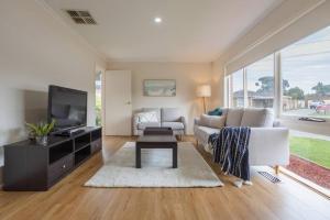 a living room with a white couch and a tv at Cozy Family Friendly Werribee Home in Werribee