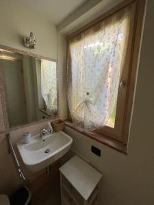 a bathroom with a sink and a window with a curtain at Piccolo Borgo in Negrar