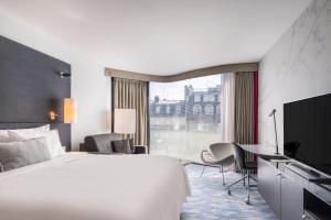 ein Hotelzimmer mit einem Bett, einem Schreibtisch und einem Fenster in der Unterkunft Renaissance Paris Arc de Triomphe Hotel in Paris