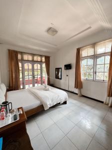 Hotel Ompu Herti في باليج: غرفة نوم كبيرة مع سرير كبير ونوافذ