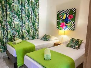 pokój hotelowy z 2 łóżkami i zieloną pościelą w obiekcie Côté Plage w mieście Saint-François