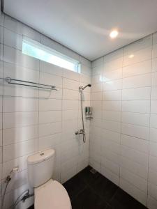 a white bathroom with a toilet and a window at Hotel Ompu Herti in Balige