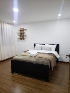 a bedroom with a large bed with white walls at Departamento completo con hermosa vista de la ciudad in Cuenca