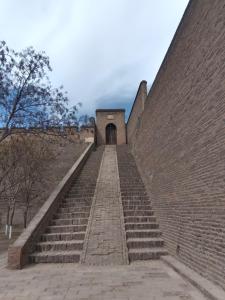 a set of stairs leading up to a brick wall at Pingyao hu lu wa Home Inn in Pingyao