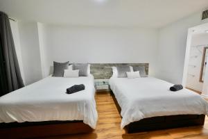 two beds in a room with white walls and wood floors at City & Sea View+FREE Parking Modern Condo in Miami