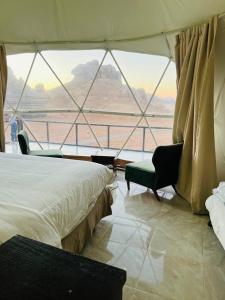 a bedroom with a bed and a chair and a window at Wadi Rum Rose camp in Wadi Rum