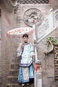 a woman in a dress holding an umbrella at Pingyao hu lu wa Home Inn in Pingyao