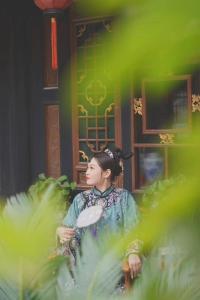 a woman sitting on a chair in front of a building at Pingyao hu lu wa Home Inn in Pingyao