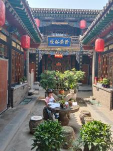 a person sitting at a table in front of a building at Pingyao hu lu wa Home Inn in Pingyao