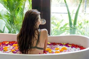 una donna seduta in una vasca da bagno piena di fiori di Botanika Estate 3 BR Private Pool Villa - 15 mins to the beach a Canggu