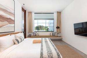 una camera da letto con un grande letto bianco e una finestra di Botanika Estate 3 BR Private Pool Villa - 15 mins to the beach a Canggu