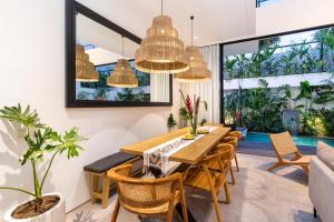 a dining room with a wooden table and chairs at Botanika Estate 3 BR Private Pool Villa - 15 mins to the beach in Canggu