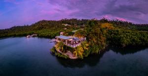 an island with a house in the middle of the water at Edgewater Dive & Spa Resort in Puerto Galera