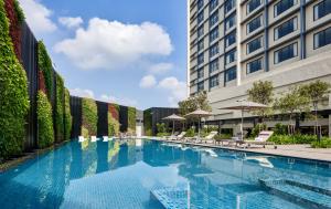 a swimming pool with chairs and a building at Hyatt Place Johor Bahru Paradigm Mall in Johor Bahru