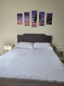 a bedroom with a bed with three paintings on the wall at Casa de Praia - Búzios in Búzios