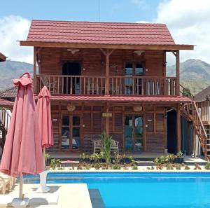 a log cabin with a pool and umbrellas at Melasti Mountain Villas, Amed, Room 1, Agung Guesthouse, in Amed