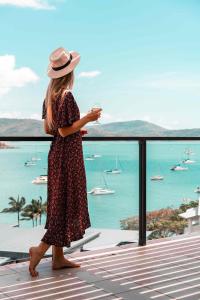 una donna in piedi su un balcone con un bicchiere di vino di Mirage Whitsundays ad Airlie Beach