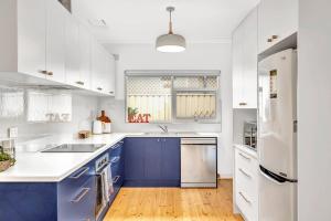 a kitchen with blue cabinets and a white refrigerator at Beachtown Breeze - A Coastal Gem in Glenelg East in Glenelg