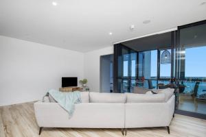 a white couch in a living room with glass windows at Como Prestige Breathtaking Southport Sundale in Gold Coast