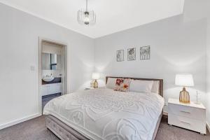 a white bedroom with a bed and two lamps at Stellar - Spacious Rooftop Dreamscape in Adelaide in Rose Park