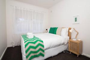 a bedroom with a bed with a green and white blanket on it at Cranbrook Courtyard - A Sunny City-fringe Retreat in Wayville