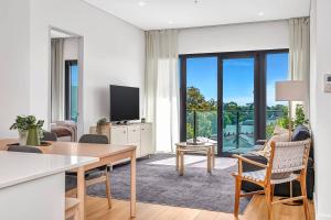 a living room with a table and chairs and a tv at 'The Outlook' Light-filled Nordic Contemporary in Glenunga