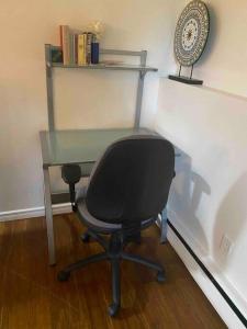 a desk with a chair and a glass table at Beautiful two bedroom apartment. in Calgary
