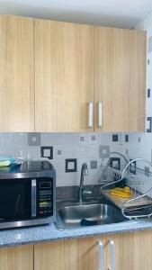 eine Küche mit einer Spüle und einer Mikrowelle in der Unterkunft Cómodo apartamento en Santiago in Licey al Medio