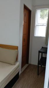 een slaapkamer met een bed, een raam en een deur bij Suíte Independente - Praia Indaiá e Riviera - MarDoceLar Bertioga in Bertioga