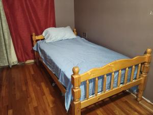 a wooden bed with a blue comforter and a pillow at OC House in Santa Ana