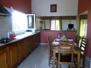 uma cozinha com uma mesa de madeira, uma mesa e cadeiras em TAMPON - Villa au calme,Vue Panoramique, SPA,SAUNA em Le Tampon